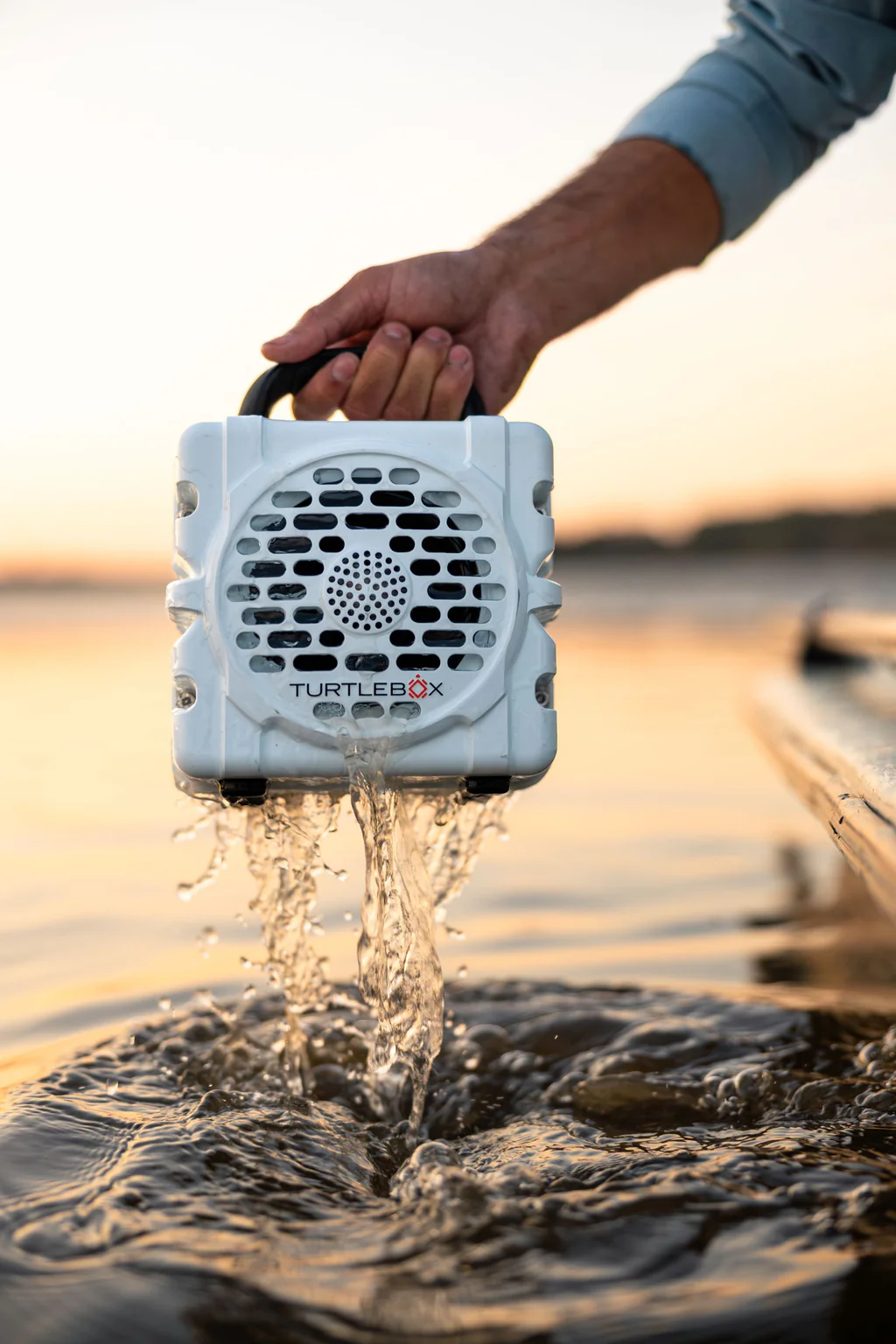 Turtlebox Cub waterproof speaker draining from the water at sunset